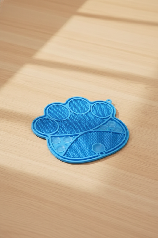 Blue paw-shaped silicone lick mat on warm pale oak surface — kept. v2